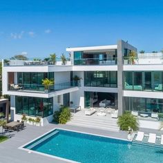 an aerial view of a modern house with pool and lounge chairs in the foreground