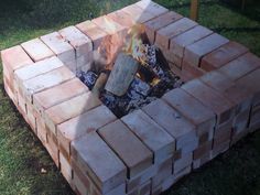 a fire pit made out of bricks in the grass