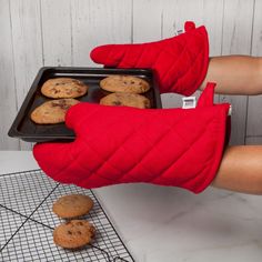 a person in red mitts holding a tray of cookies