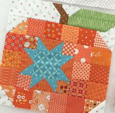 an orange and blue patchwork quilt on top of a piece of paper with scissors