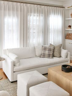 a living room with white furniture and curtains