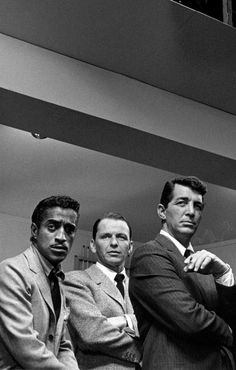 black and white photograph of three men in suits standing next to each other with their arms crossed