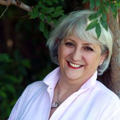 an older woman smiling next to a tree