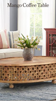 a coffee table with flowers on it in front of a couch