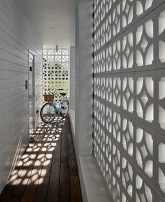 a bike is parked in front of a white wall with geometric designs on it and a wooden floor