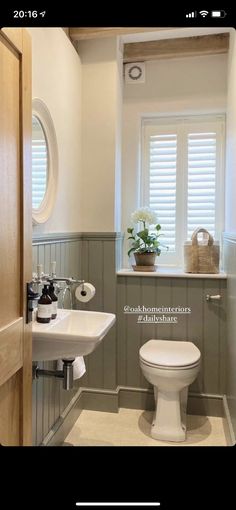 a white toilet sitting next to a sink in a bathroom under a window with shutters