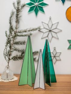 three green and white christmas trees sitting on top of a wooden table