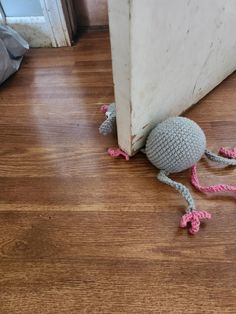 a crocheted rat crawling on the floor next to an open door with pink feet