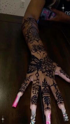 a woman's hand with hendix and flowers painted on her hands, sitting on a table