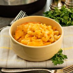 a bowl filled with macaroni and cheese on top of a table next to silverware