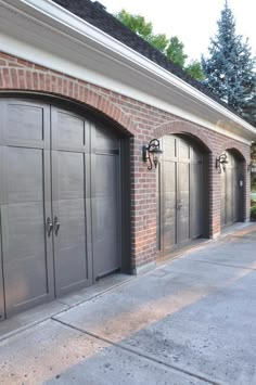 two garage doors are open on the side of a brick building with an arched doorway