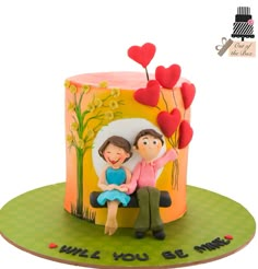 a cake with a couple sitting on top of it and hearts flying out of the top