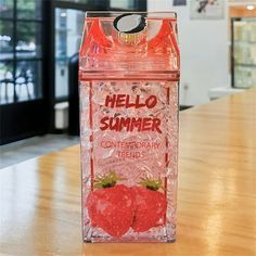 a plastic container with strawberries on it sitting on top of a wooden table in front of a window