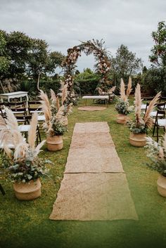 an outdoor ceremony setup with chairs and flowers in planters on the grass, surrounded by greenery