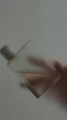 a person's hand holding an object in the air with water droplets on it