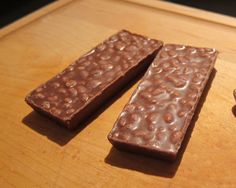 two pieces of chocolate sitting on top of a wooden cutting board