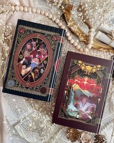 two books sitting next to each other on top of a table covered in beads and pearls