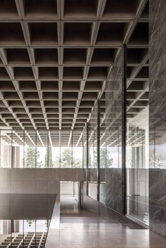 the inside of an empty building with glass walls and stairs leading up to it's second floor