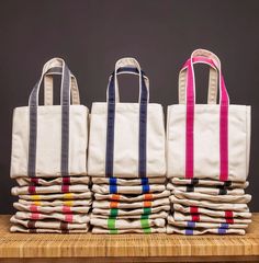 three bags are stacked on top of each other in front of a stack of folded ones