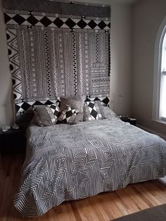 a bed with black and white bedspread next to a window