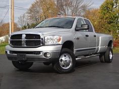 a silver dodge ram truck parked in a parking lot next to trees and power lines