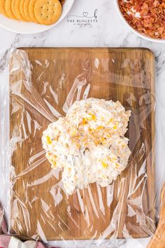 a wooden cutting board topped with cheese and crackers