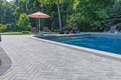 an empty swimming pool with lounge chairs and umbrellas next to it, surrounded by trees