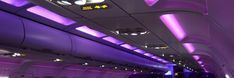 the inside of an airplane with purple lighting and lights on it's ceiling is shown