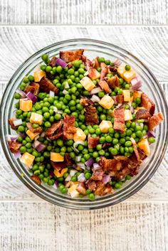 a bowl filled with peas and bacon on top of a table