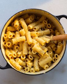 a pot full of macaroni and cheese with a wooden spoon