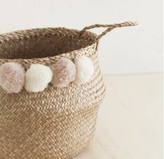 a basket with three pom - poms hanging from it's sides on a table