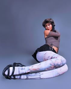 a woman is sitting on the ground with her legs crossed and wearing leggings