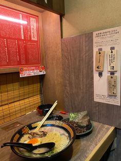 a bowl of noodles and chopsticks on a table in front of a menu