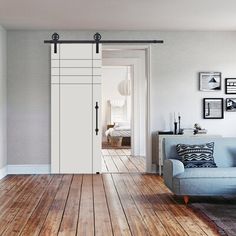 a living room with wood floors and white doors leading to another room that has a blue couch in front of it