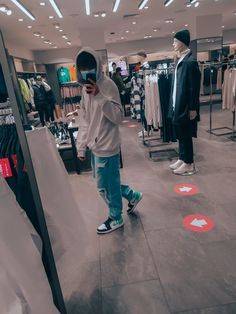 a man is looking at his cell phone while standing in the middle of a clothing store