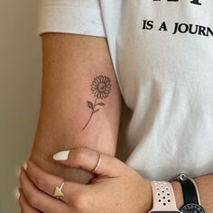 a woman's arm with a small flower tattoo on the left side of her arm