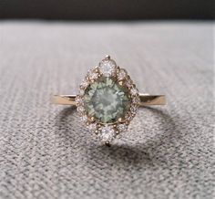 a green and white diamond ring sitting on top of a gray carpeted tablecloth