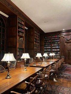 a long table with chairs and lamps in a library