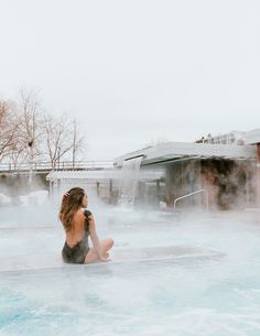 a woman sitting in the middle of a hot tub with steam coming out of it