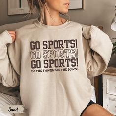 This cozy sweatshirt with "Go Sports" is a must-have Funny Game Day Shirt for any laid-back fan. Perfect as a Sports Mom Shirt or a Funny Girl Sports crewneck, it's a playful choice for soccer, basketball, or football moms who cheer for all the teams with equal enthusiasm. Prefer this design on a T-Shirt? Visit this link:  Everything You Need to Know: 🧥 Sweatshirt Brand Gildan | Unisex Adult Sizing | 50% Cotton, 50% Polyester ⏳🚚 Production & Shipping All items are made-to-order. They will ship within 1-5 business days from one of our printing partners, shipping usually takes between 2-5 business days after the item is shipped. Please allow sufficient time for production and shipping.  Important: Please double-check your shipping address before checking out. A fee will apply if an order n Sporty Sweats For Sports, Sportswear Sweats With Graphic Print For Sports, Graphic Print Sweats For Sports, Athleisure Sports Sweats With Letter Print, Sporty Athletic Heather Sweats For Sports, Athleisure Sweats With Letter Print For Sports, Sporty Workout T-shirt For Fall, Fall Sports T-shirt With Letter Print, Winter Sports T-shirt