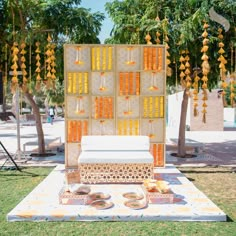 an outdoor seating area with orange flowers and candles hanging from the tree's branches