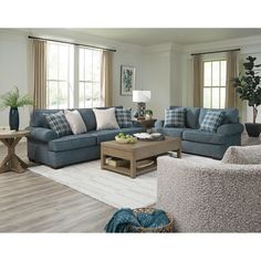 a living room with couches, chairs and a coffee table in front of two windows