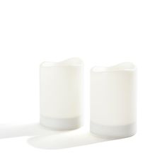 two white candles sitting next to each other