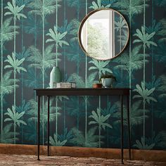 a table with a mirror on it in front of a palm tree wallpapered room