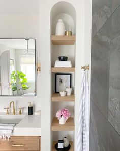 a bathroom with shelving unit, sink and mirror in the corner next to it