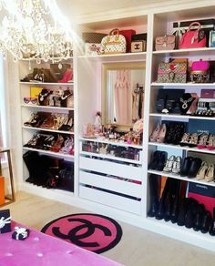 a closet filled with lots of shoes and handbags on top of shelves next to a chandelier