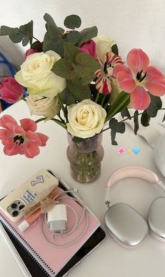 a bouquet of flowers in a vase with headphones on the table next to it