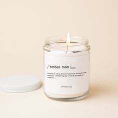 a white candle sitting on top of a table next to a small round container with a label