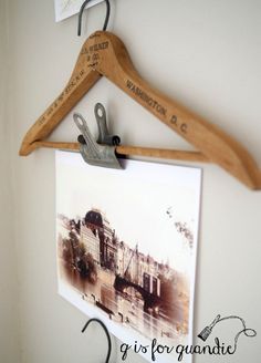 a pair of scissors hanging from a wooden hanger on a white wall next to a photograph