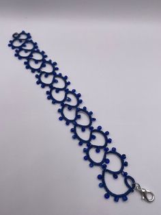 Handmade Tatted bracelet made with blue polyester thread and blue glass beads. Elegant Blue Bead Bracelet, Elegant Blue Beads Bracelet, Blue Beaded Bracelets With Spacer Beads For Party, Blue Beaded Bracelets For Party, Blue Spacer Beads Bangle Jewelry, Blue Beaded Crystal Bangle Bracelet, Adjustable Blue Crystal Bracelet With Tiny Beads, Blue Bangle With Spacer Beads, Blue Crystal Bracelet With Tiny Beads